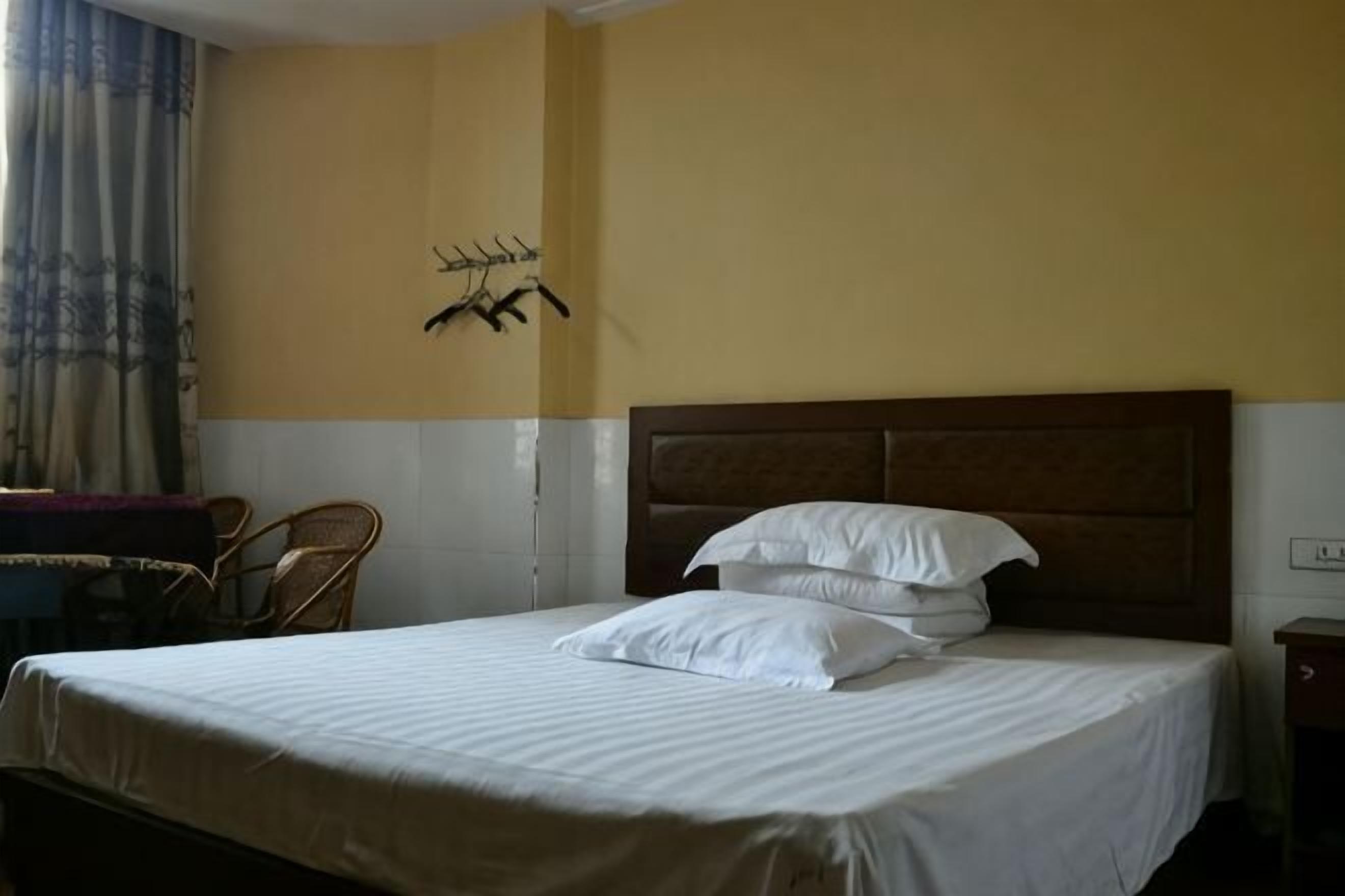 A hotel room with a bed, a chair, a small table, and a wall-mounted coat rack.