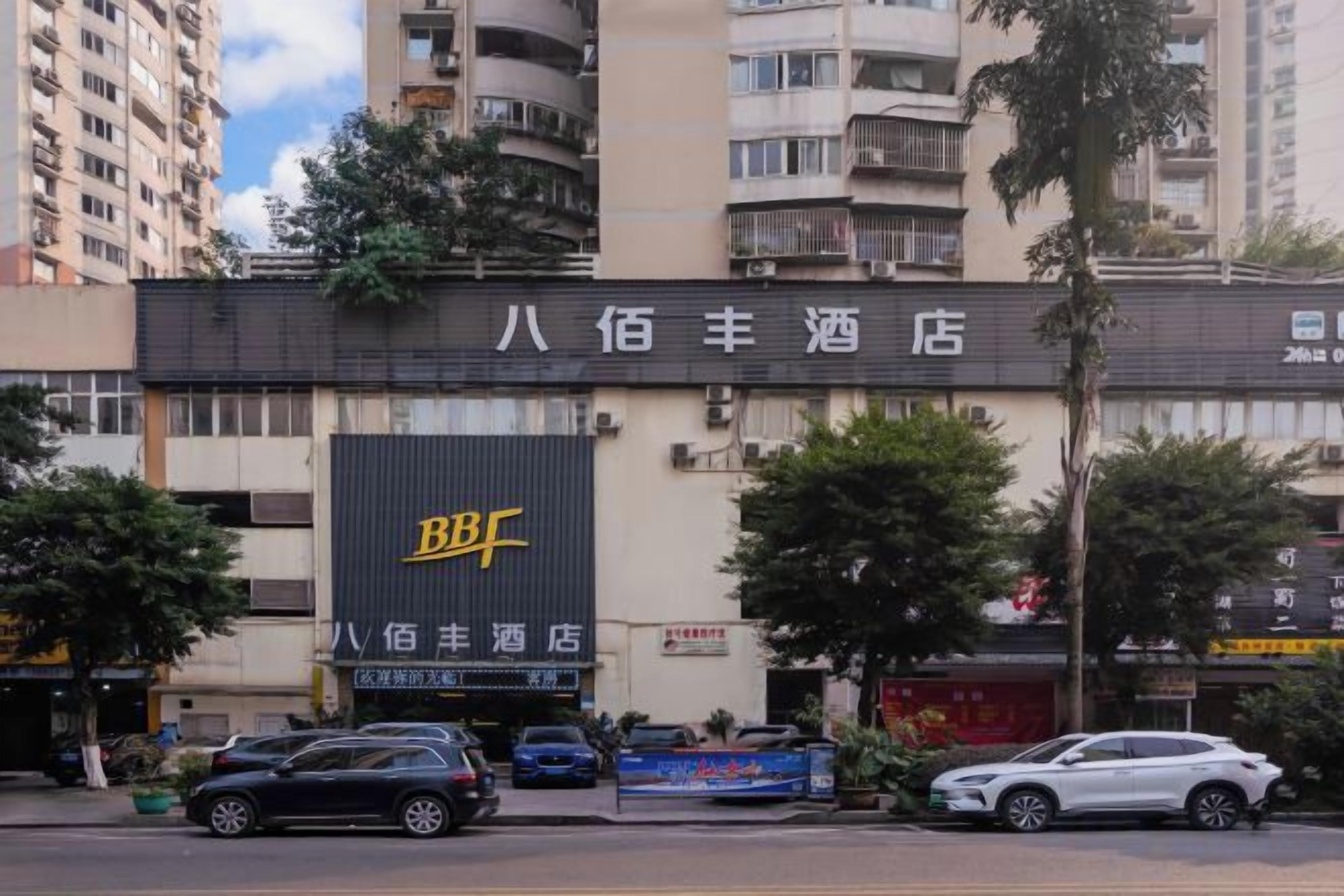 A hotel with a prominent sign, multiple floors, and a parking area in front.