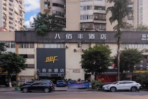 A hotel with a prominent sign, multiple floors, and a parking area in front. - Chongqing Ba Bai Feng Traders Hotel (Chongqing)