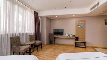 A hotel room with two beds, a desk with a TV, a chair, and a small table.