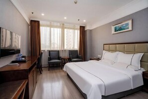 Una habitación de hotel con una cama grande, un escritorio con silla, una mesita pequeña y un televisor.