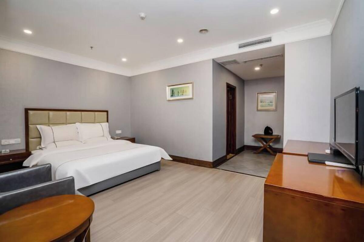 A modern hotel room with a large bed, a desk, and a television.