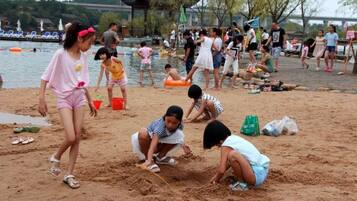 Escena de playa con gente jugando en la arena y nadando en el agua.
