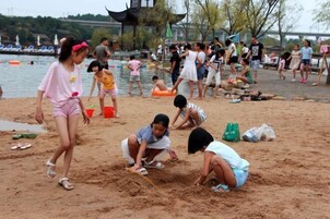 Escena de playa con gente jugando en la arena y nadando en el agua.