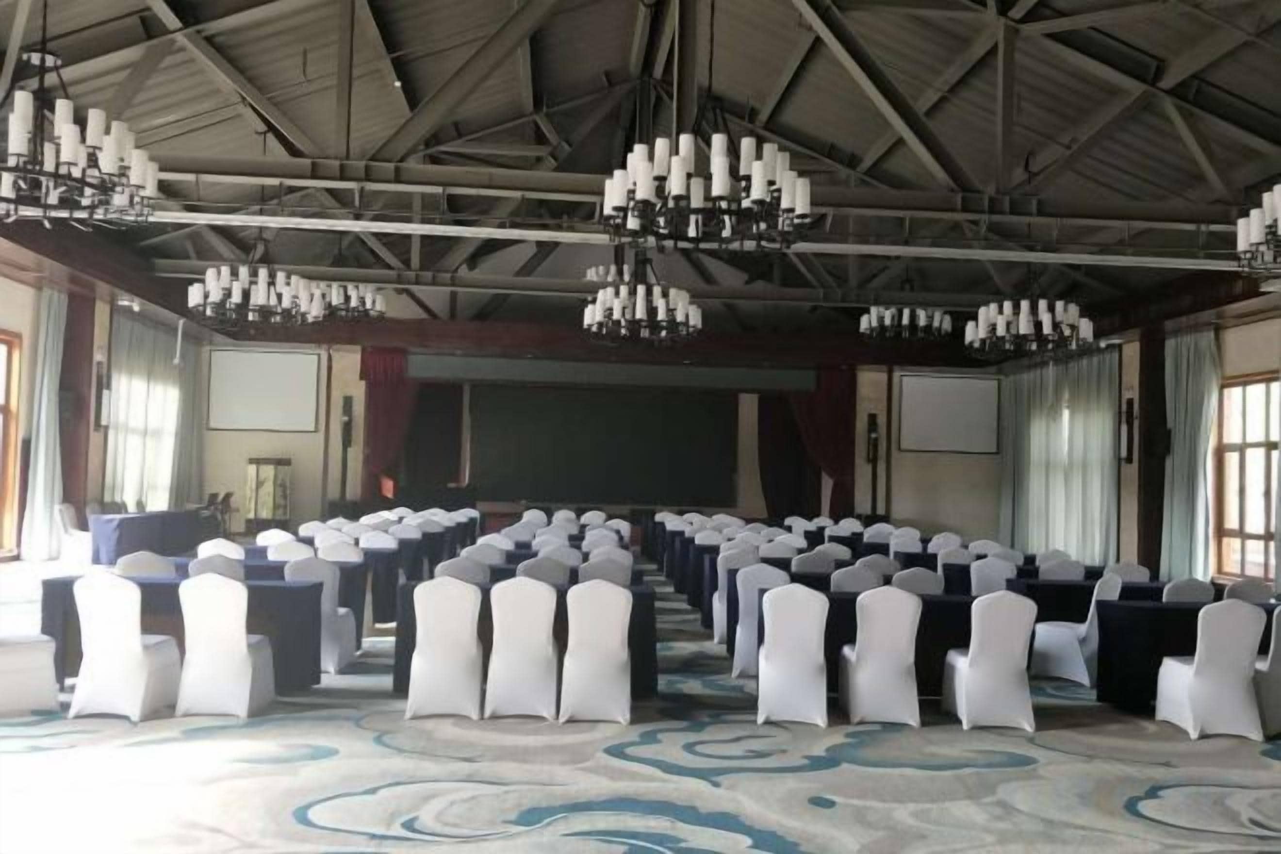 Un salón de conferencias con filas de sillas, un escenario y candelabros.