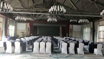 Un salón de conferencias con filas de sillas, un escenario y candelabros.