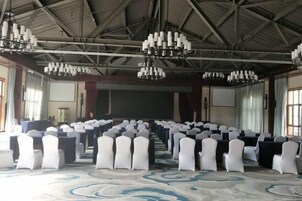Un salón de conferencias con filas de sillas, un escenario y candelabros.