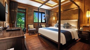 Un dormitorio espacioso con cama con dosel, un escritorio de madera y vistas al exterior.