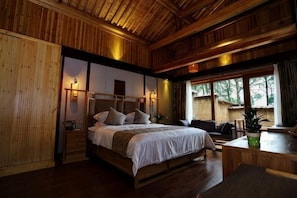 A wooden-paneled room with a bed, bedside table, and a window.