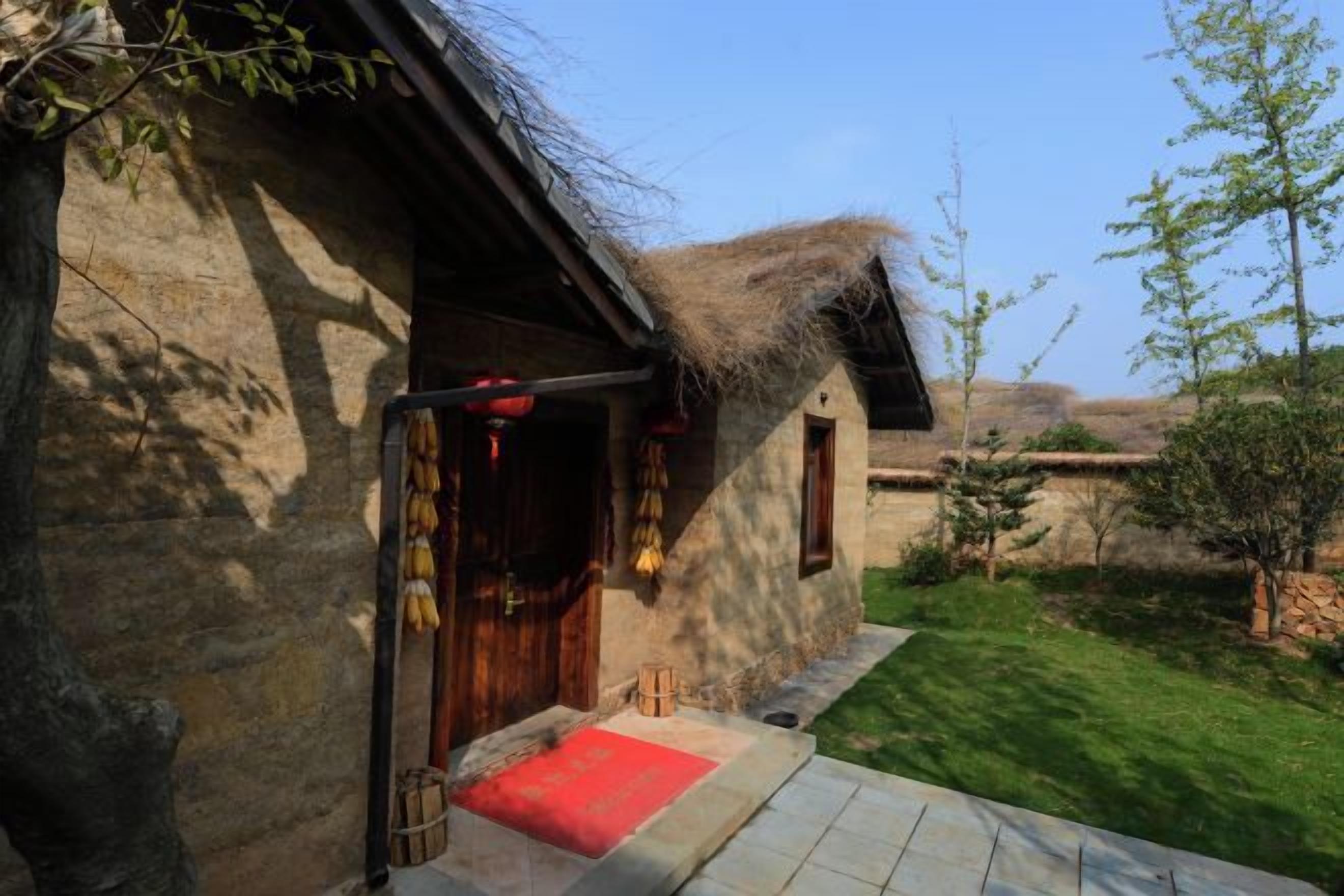 A rustic stone building with a wooden door and a red mat at the entrance.