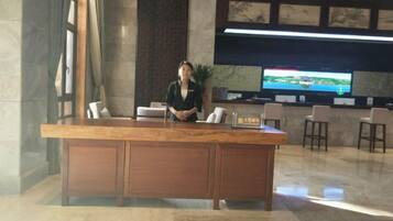 A reception desk with a receptionist, a television screen, and a seating area with chairs.
