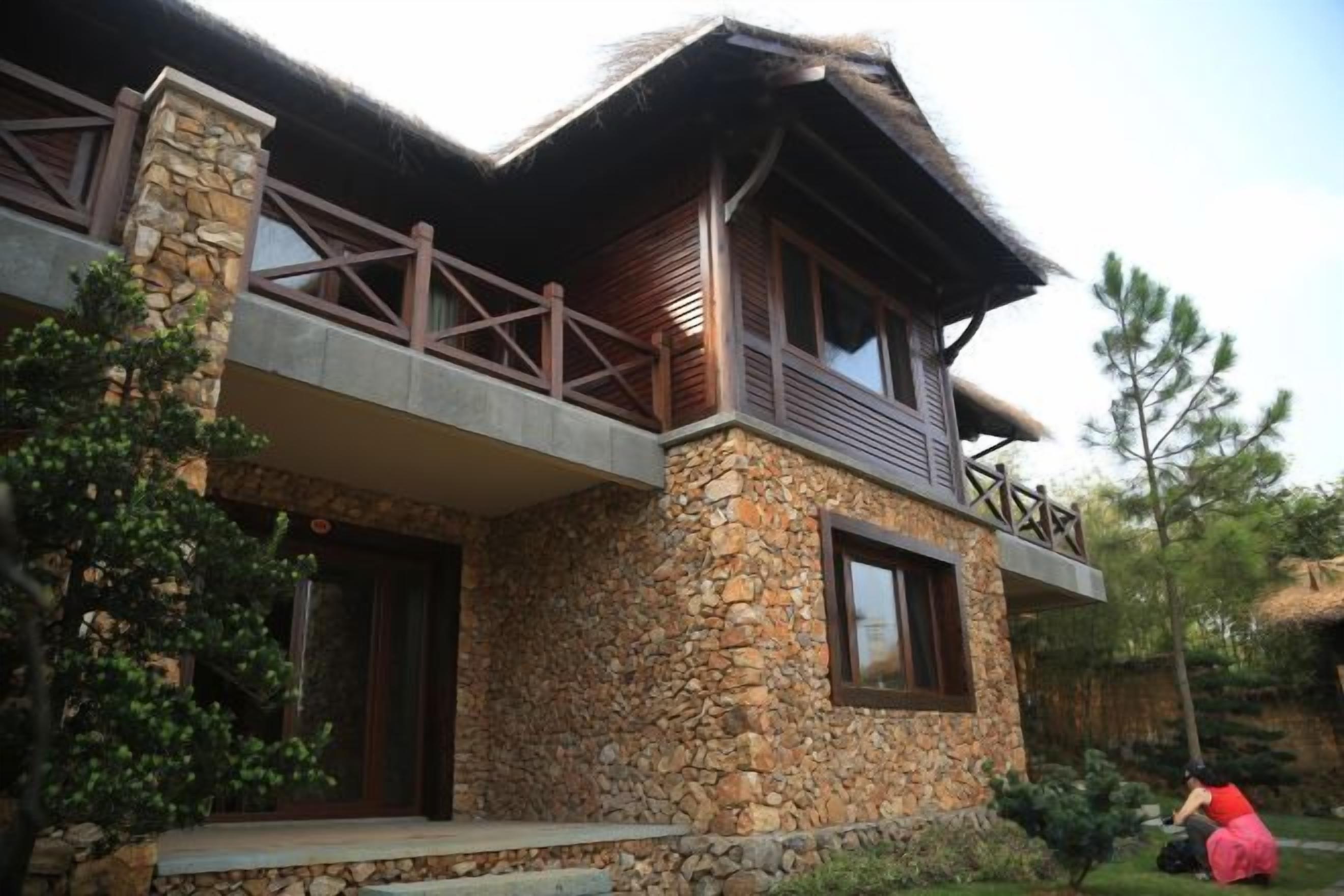 A stone house with a balcony, a wooden door, and a window.