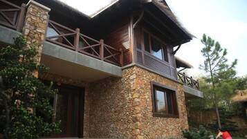 A stone house with a balcony, a wooden door, and a window.