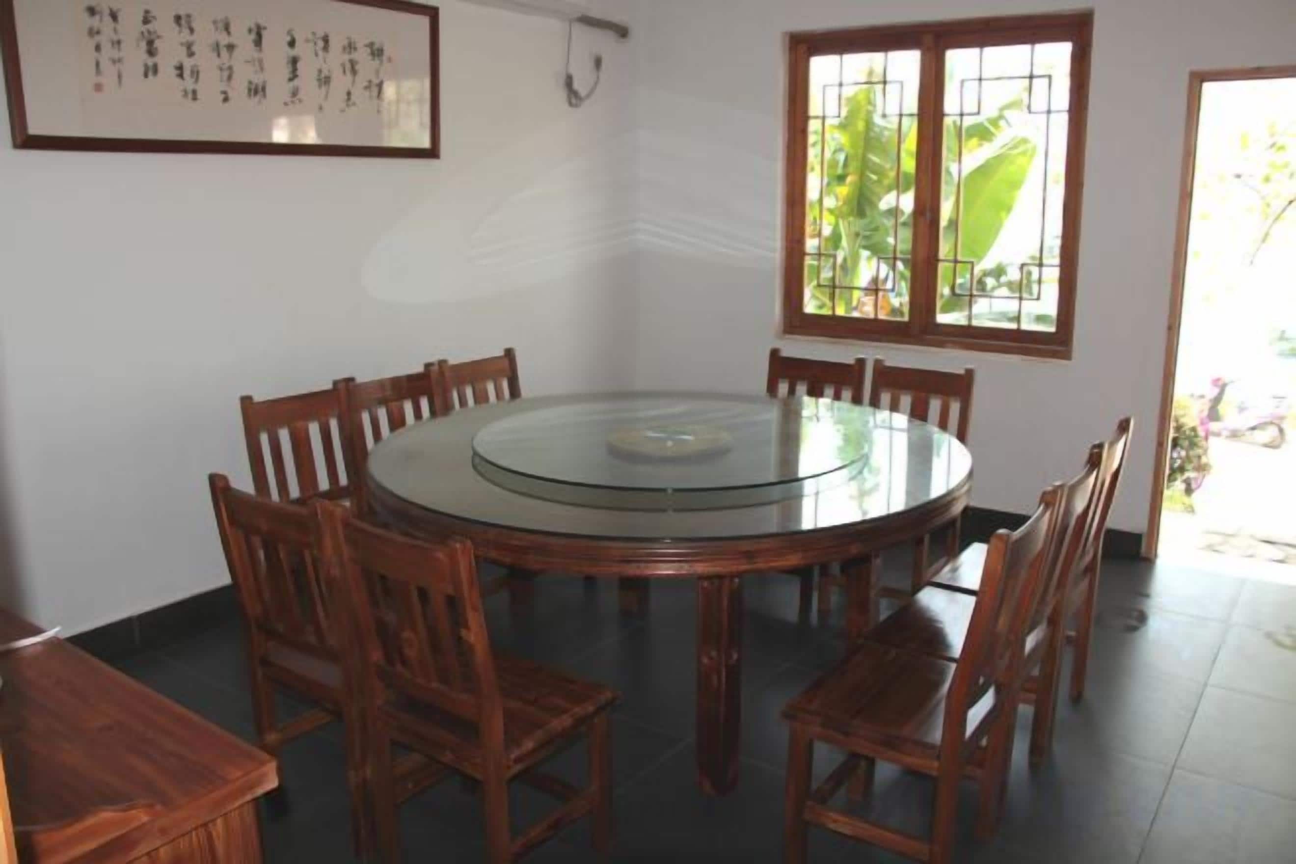 Una mesa redonda con sillas de madera, una obra de arte enmarcada en la pared y una ventana con vistas al verdor.