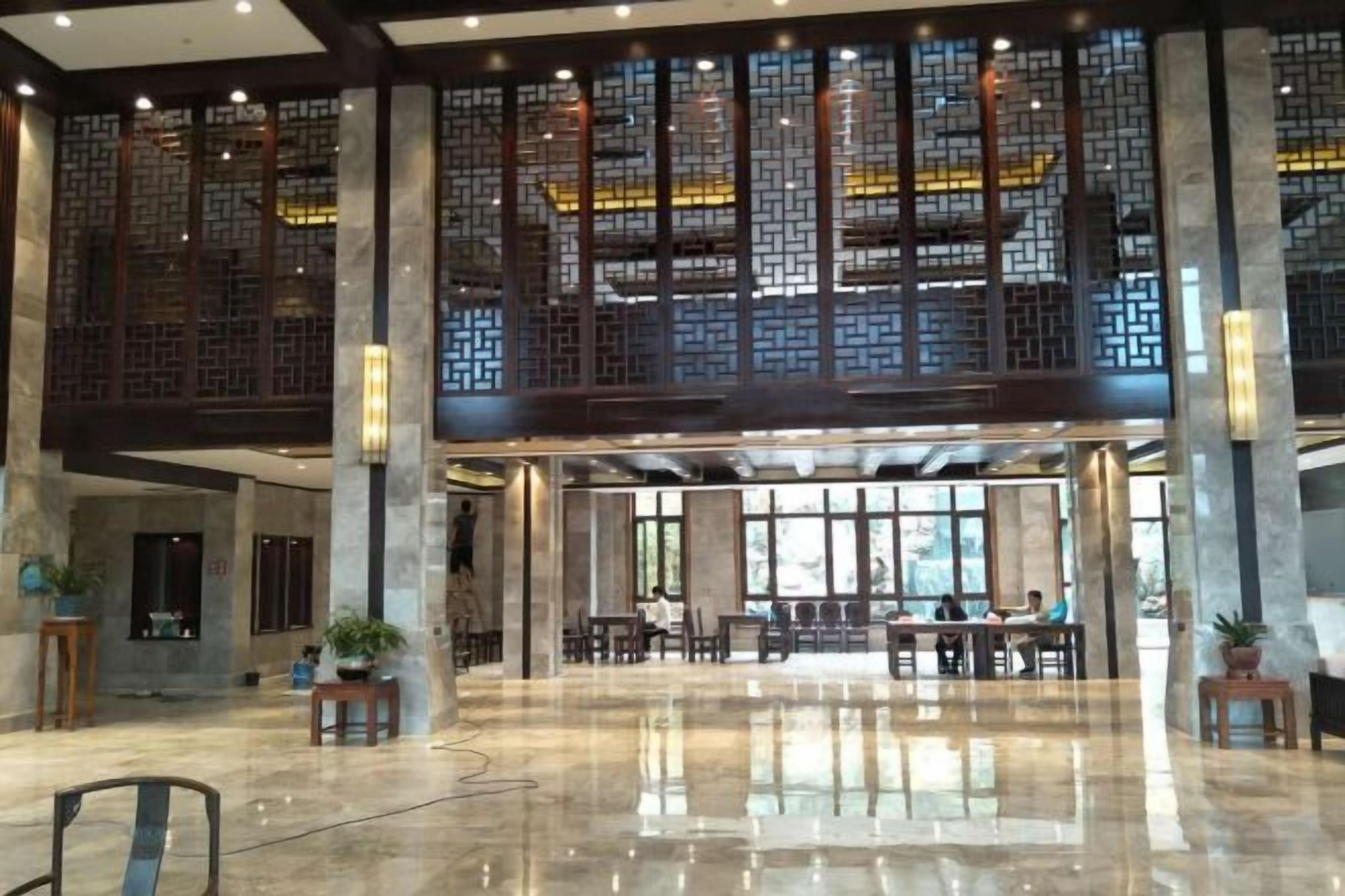 A spacious lobby with a high ceiling, large windows, and a traditional wooden screen design.