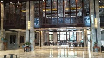 A spacious lobby with a high ceiling, large windows, and a traditional wooden screen design.