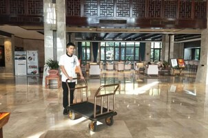 Un vestíbulo de hotel con piso pulido, una recepción y zonas de estar.