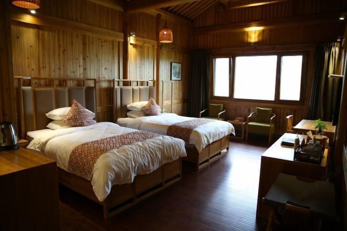 A wooden room with two beds, a desk, and a chair.