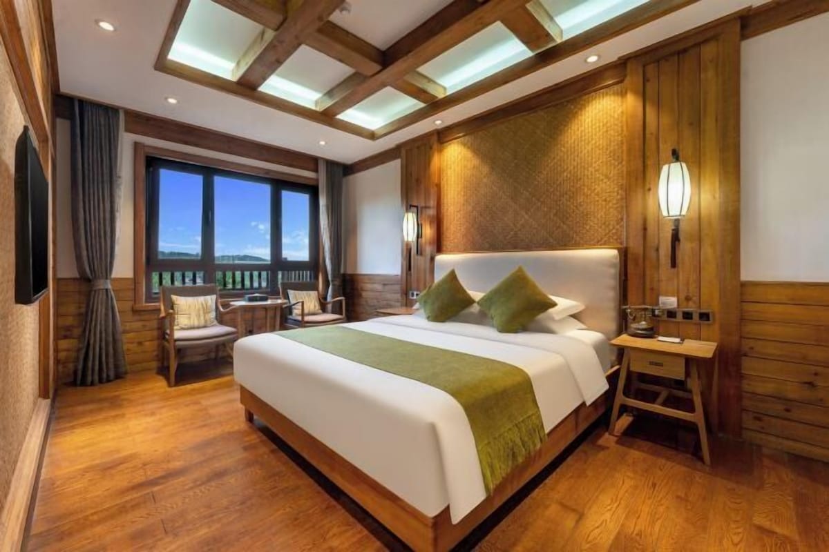 A spacious bedroom with a large bed, wooden headboard, and a view of the outdoors.