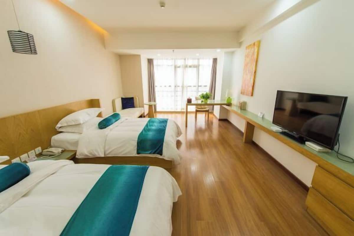A hotel room with two beds, a TV, a desk, and a chair.