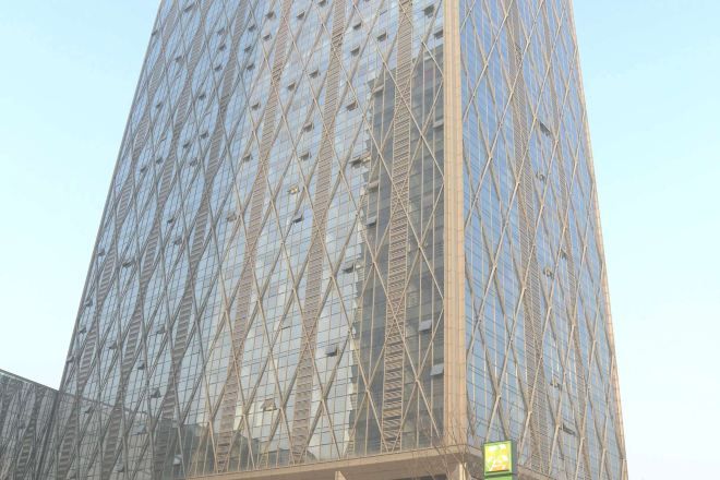 A tall building with a distinctive geometric facade, featuring a pattern of diamond shapes and a grid-like structure.