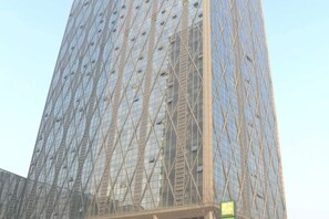 A tall building with a distinctive geometric facade, featuring a pattern of diamond shapes and a grid-like structure. - Ginkgo Hotel (Xuzhou)
