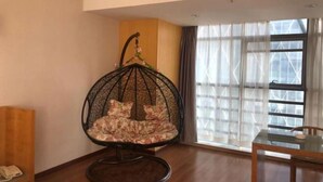 Una habitación con una silla colgante, una mesa y un ventanal con cortinas.