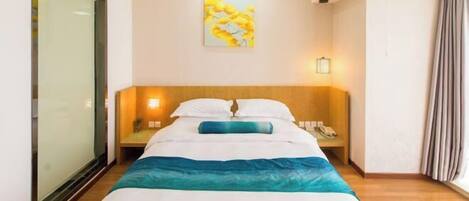Una habitación de hotel con una cama, mesitas de noche, un cuadro en la pared y una ventana con cortinas.