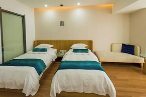 A hotel room with two single beds, a sofa, a small table, and a sliding door. - Ginkgo Hotel (Xuzhou)
