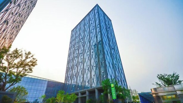 Un edificio moderno con una fachada geométrica distintiva y un exterior de vidrio reflectante.