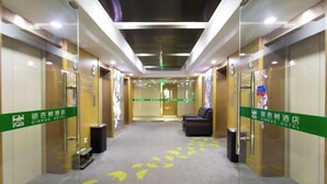 Un vestíbulo de hotel con diseño moderno, que incluye un mostrador de recepción, zona de estar y flechas direccionales en el suelo.