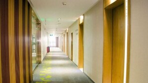 Un largo y estrecho pasillo de hotel con paneles de madera a un lado y suelo alfombrado.