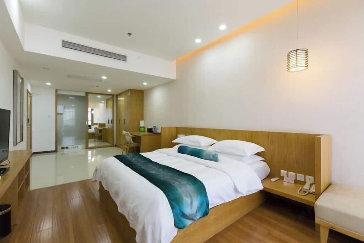 A modern hotel room with a wooden bed, bedside table, and a television.
