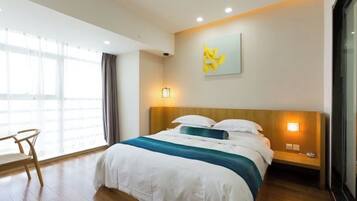 A hotel room with a large bed, a wooden nightstand, a chair, and a window with curtains.