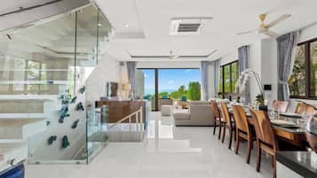 Un interior moderno con zona de comedor, pared de vidrio y vistas al exterior.