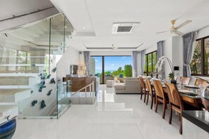 Un interior moderno con zona de comedor, pared de vidrio y vistas al exterior.
