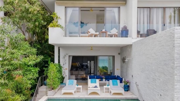 A modern two-story building with a swimming pool, lounge chairs, and a balcony. - Shades of Blue (Koh Samui)