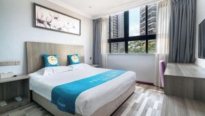 Una camera d'albergo con un letto grande, una scrivania, una sedia, una finestra con tende e un quadro appeso al muro.