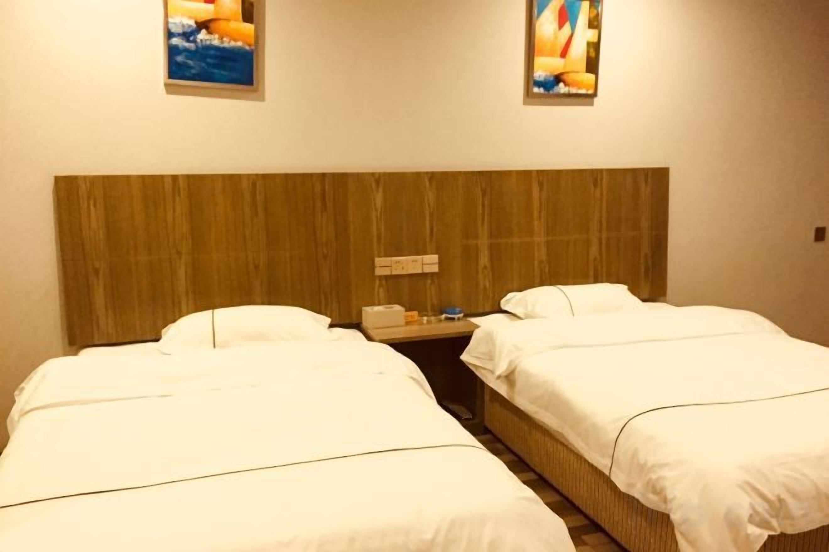 A hotel room with two beds, a wooden headboard, and artwork on the walls.