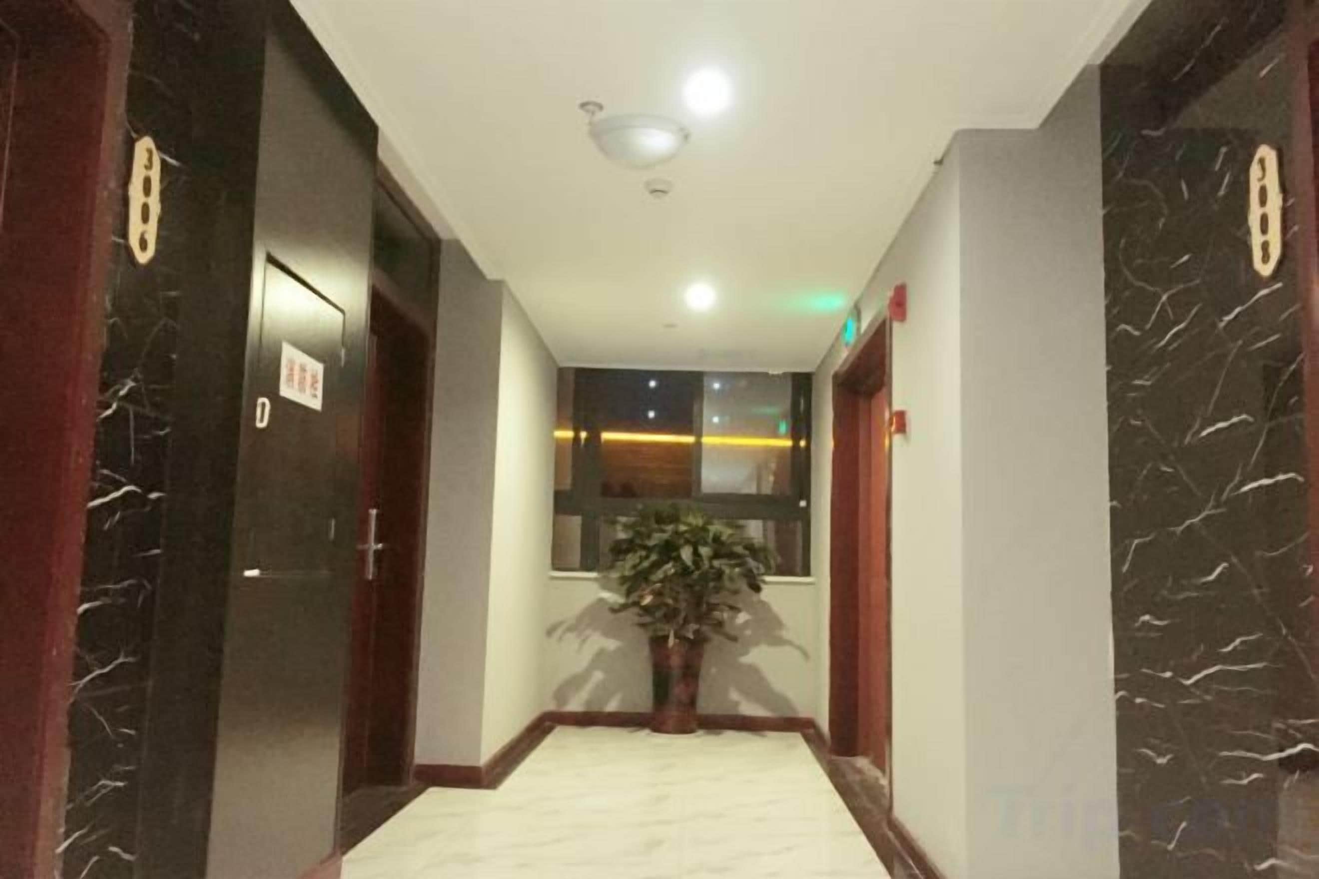 Un pasillo de hotel con suelo de mármol, puertas de madera y una planta en maceta.