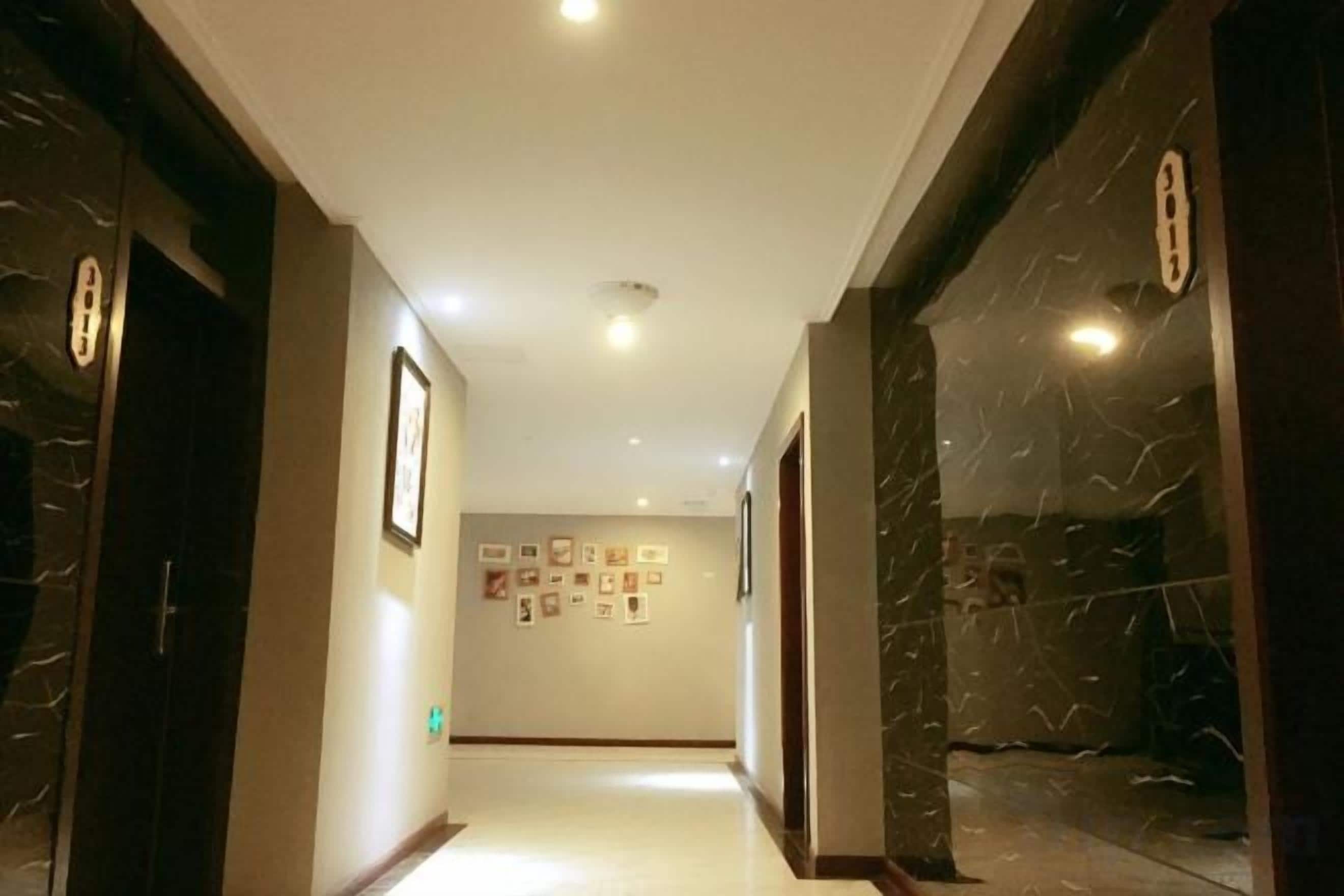A hallway with marble walls and doors, leading to a room with a tiled floor.