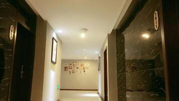 A hallway with marble walls and doors, leading to a room with a tiled floor.
