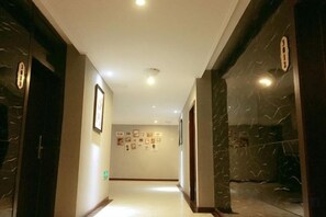 A hallway with marble walls and doors, leading to a room with a tiled floor. - lemon hotel (Chongqing)
