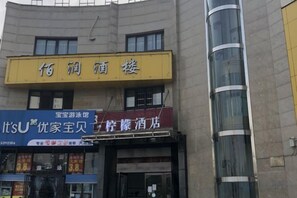 A hotel with a yellow signboard and a blue signboard advertising a family-friendly hotel. - lemon hotel (Chongqing)