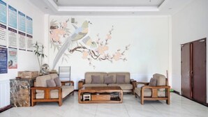 Un soggiorno con divano, tavolino e un murale con uccelli e fiori.