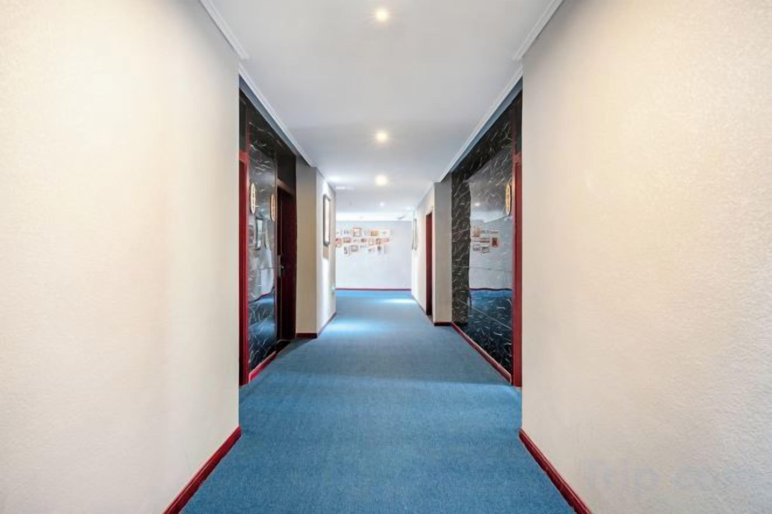 A corridor with a blue carpet, white walls, and doors with glass panels.