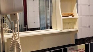 A bathroom with a mirror, a towel rack, and a shelf with toiletries. - Haihao Business Hotel (Chongqing)