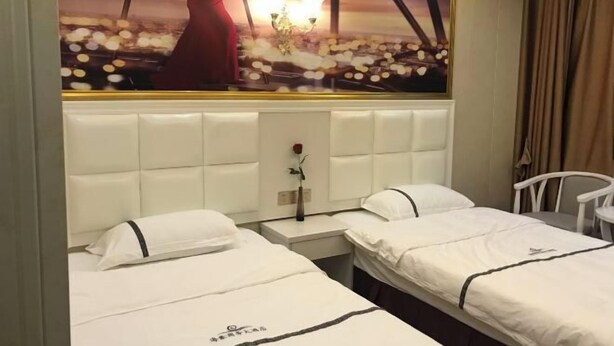 A hotel room with two beds, a large window with a cityscape view, a white headboard, and a small table with a vase of flowers. - Haihao Business Hotel (Chongqing)