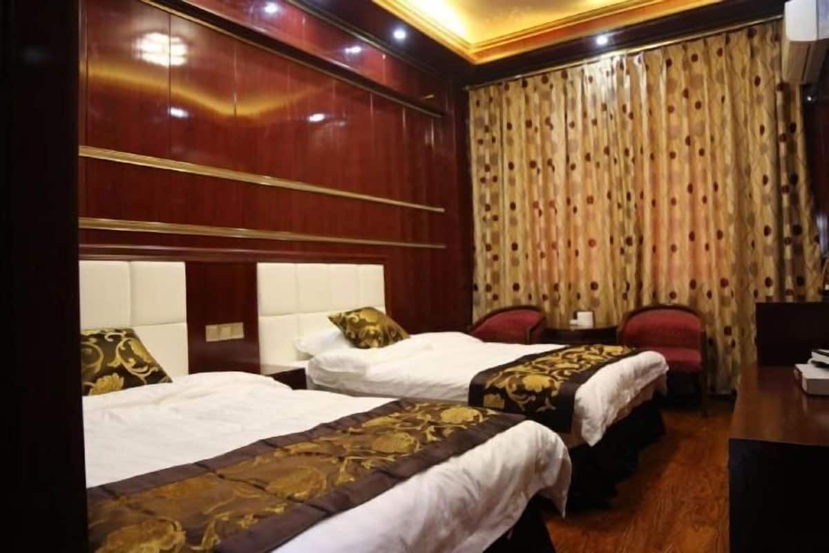 A hotel room with two beds, a desk, and a chair.