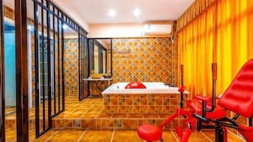 A bathroom with a bathtub, a red chair, and a mirror.